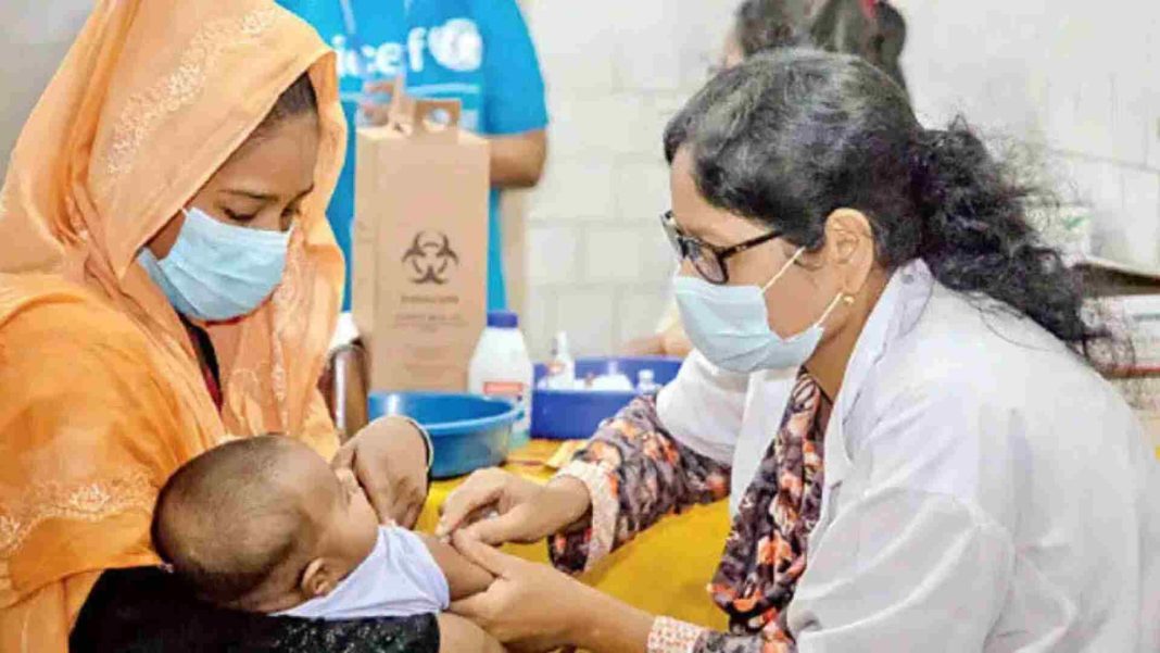 স্বাস্থ্যকর্মী একটি শিশুকে টাইফয়েড টিকা দিচ্ছেন